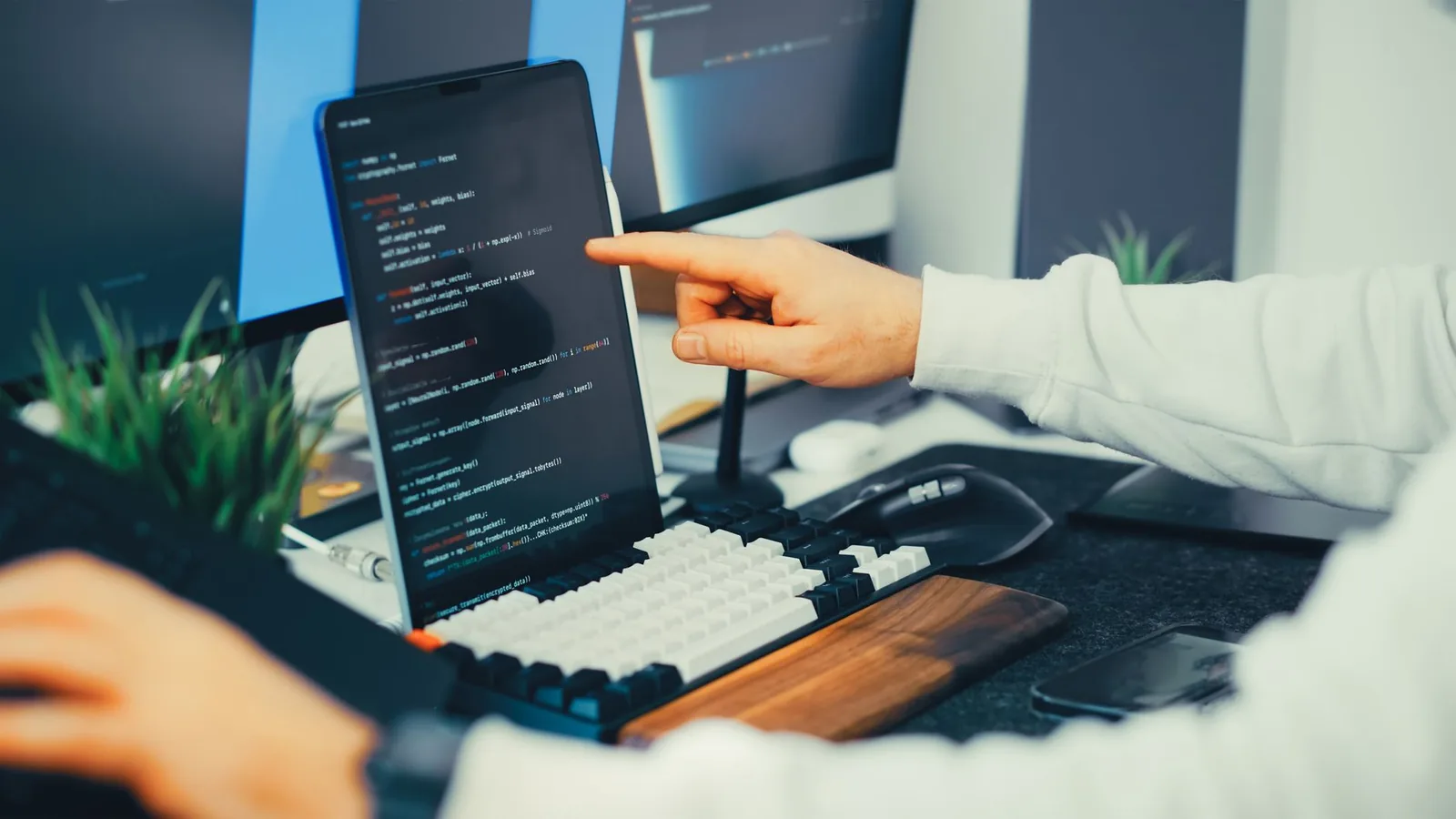 Programador aponta para código na tela durante a migração do banco para o CNPJ alfanumérico